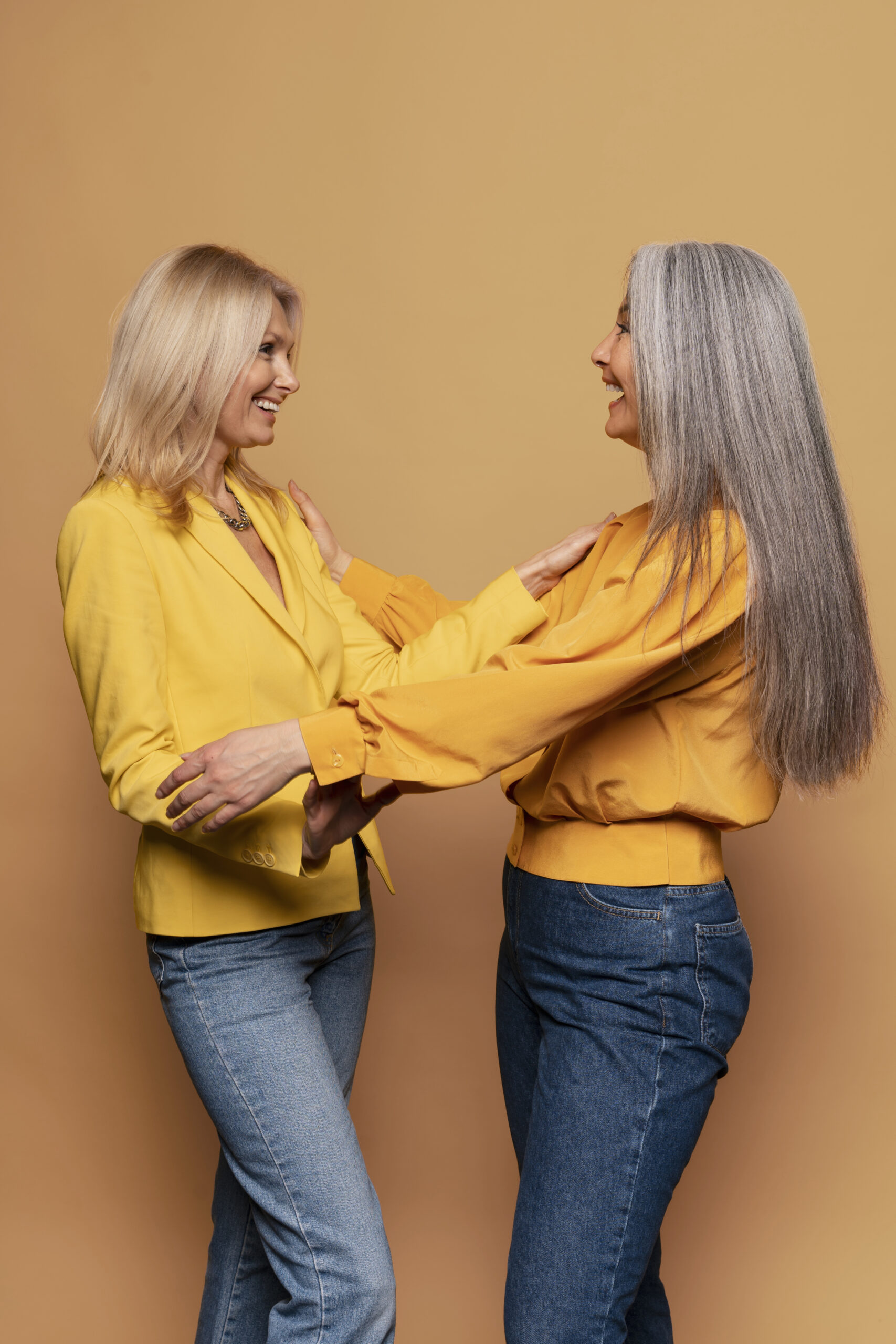 senior-women-holding-each-other-against-yellow-background