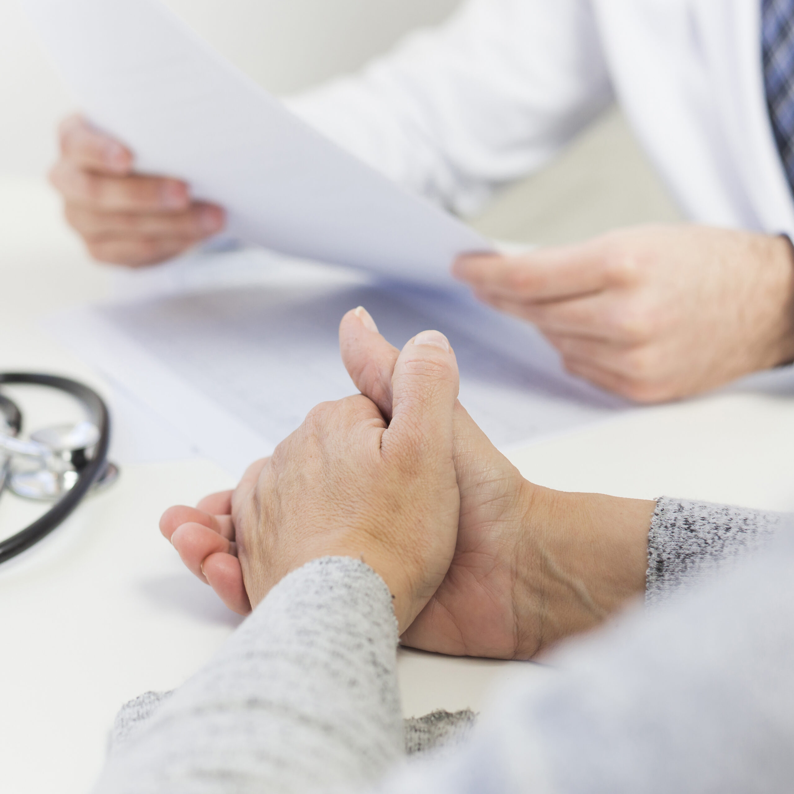 close-up-female-patient-sitting-near-doctor-holding-medical-report