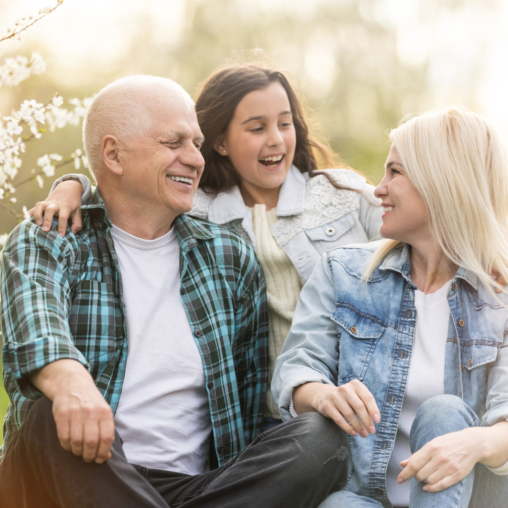 senior man grandfather sitting on outdoor in the park. Elderly retired male relax and enjoy outdoor activity together with daughter and granddaughter. Family relationship concept.