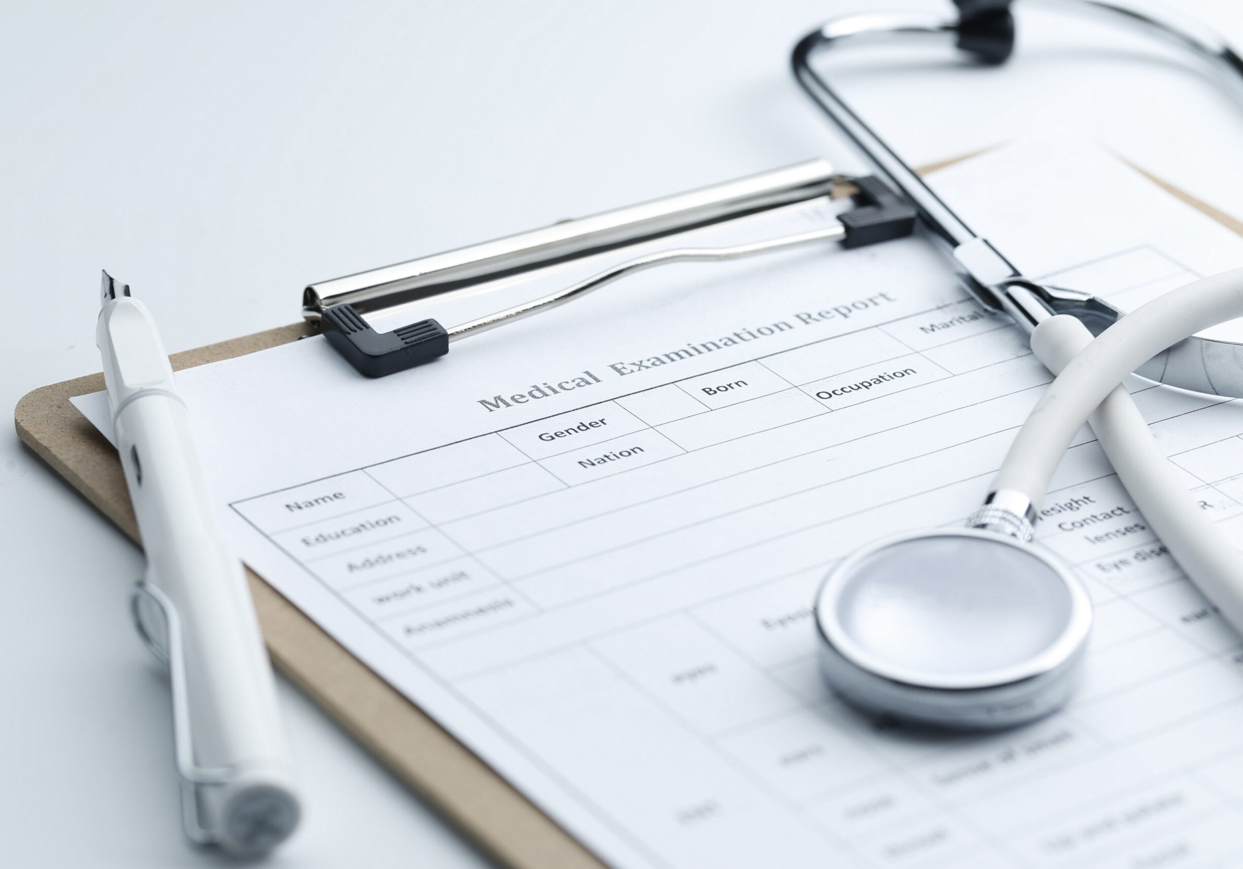 Medical examination report and stethoscope on white desktop