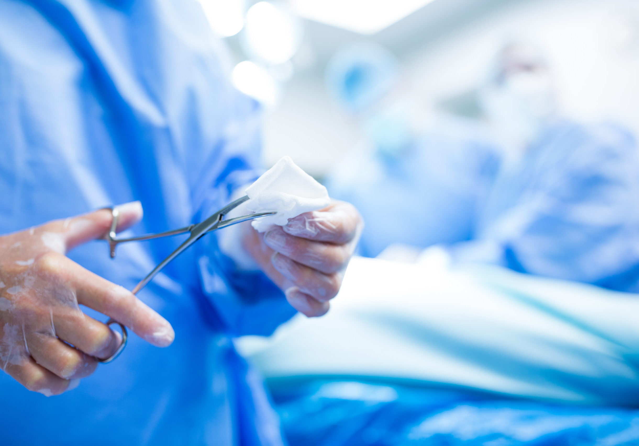 Surgeon cutting cotton from scissor in operation room at hospital